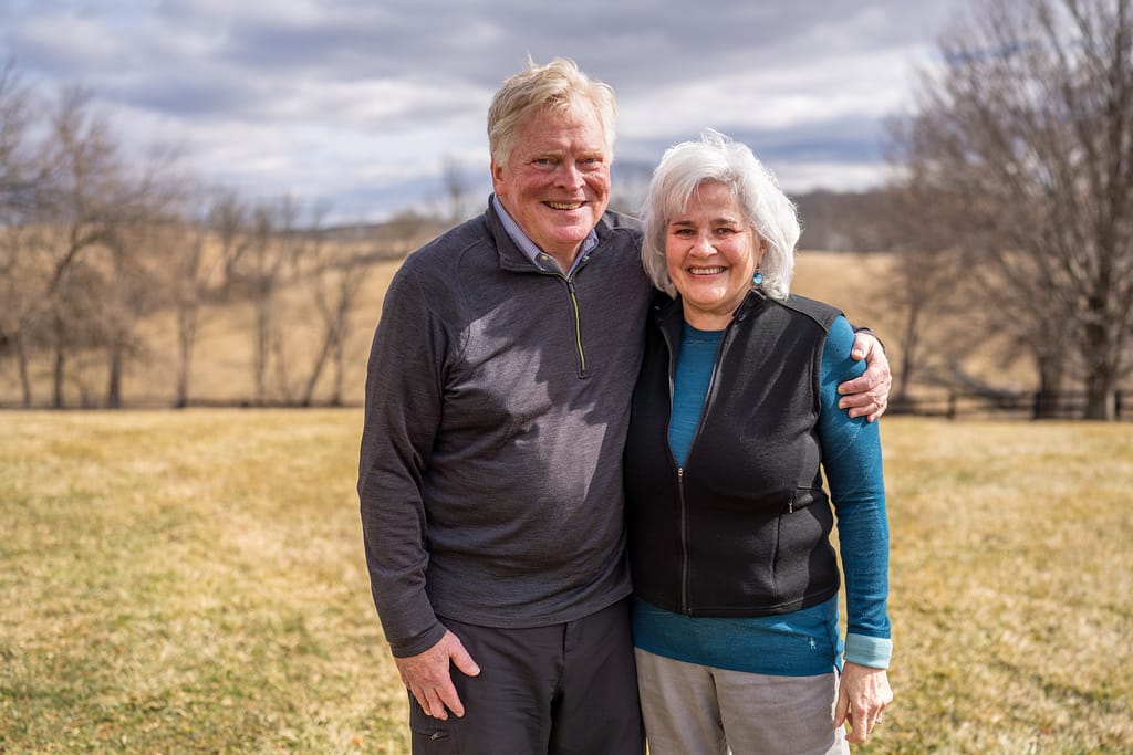 a couple stands together on their rural farm property
