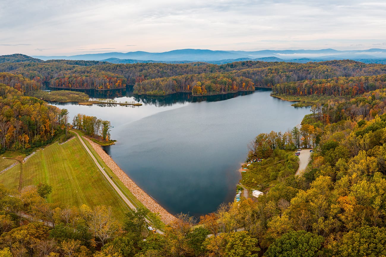 aerial image of a large resevoir surrounded by autumn forest