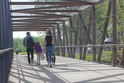 People walk across a metal bridge.