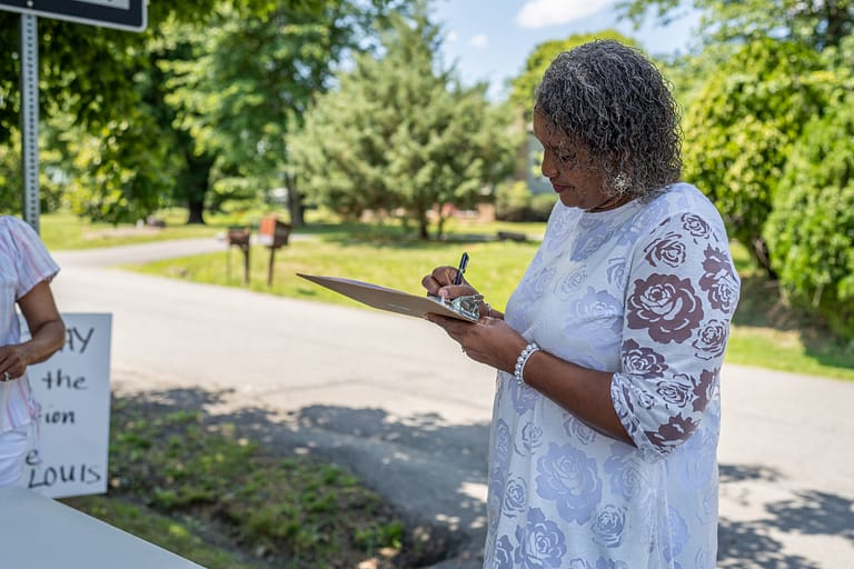 a Black woman signs a petition in St. Louis